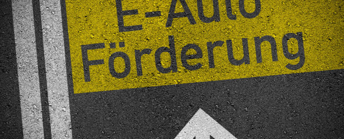 Ladeinfrastruktur-Förderung symbolisiert durch eine Markierung auf Asphalt mit dem Text "E-Auto Förderung".